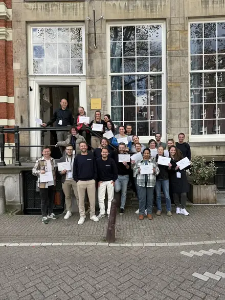 Participants holding certificates in front of the venue
