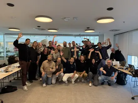 A full room of participants with their hands in the air